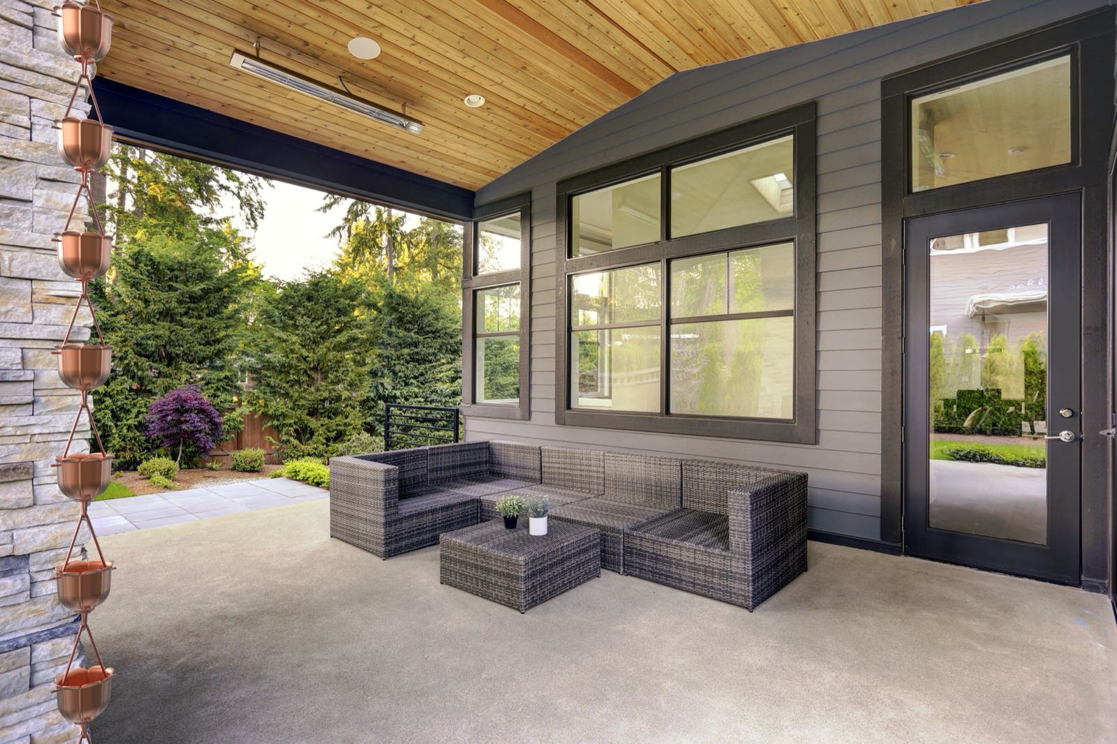 Copper fluted rain chain hanging from the eave of a modern covered patio